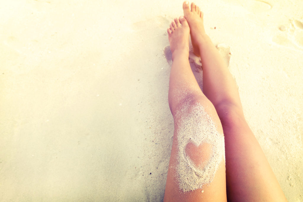 woman legs in sand heart beach